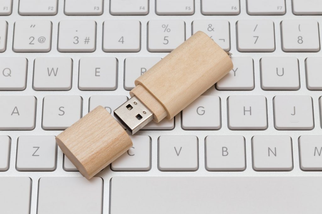 Auf einer Tastatur liegt ein USB-Stick aus Holz