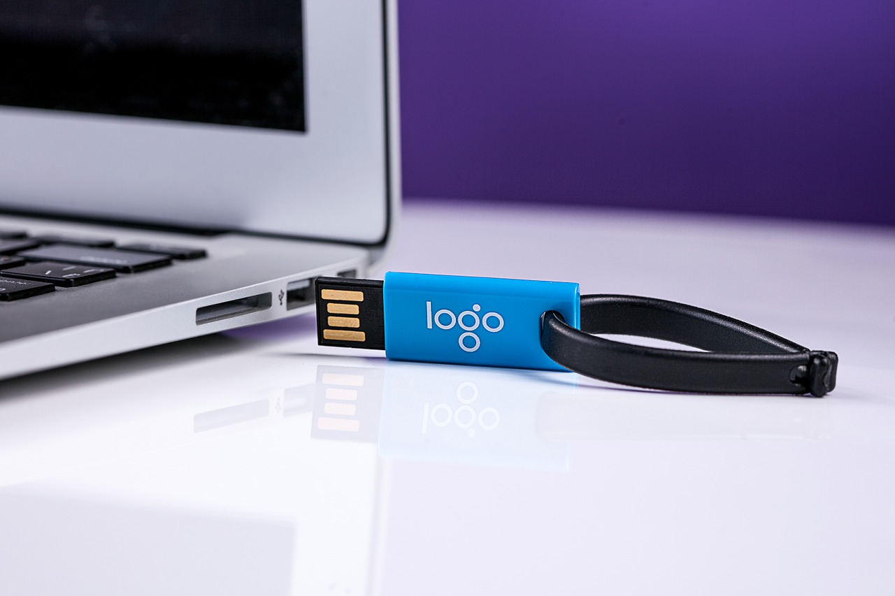 An einen Laptop wird ein blauer USB gesteckt, welcher bedruckt wurde.