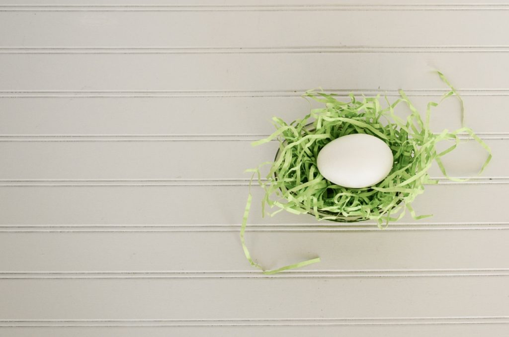 Ein Ei liegt auf grünem Ostergras aus Holzwolle
